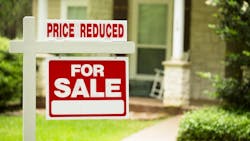 A sign in front of a house shows that the for-sale price has been reduced A sign in front of a house shows that the for-sale price has been reduced