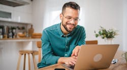 A kitchen designer using a laptop at his kitchen table A kitchen designer using a laptop at his kitchen table