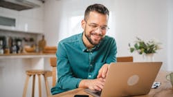 A kitchen designer using a laptop at his kitchen table A kitchen designer using a laptop at his kitchen table