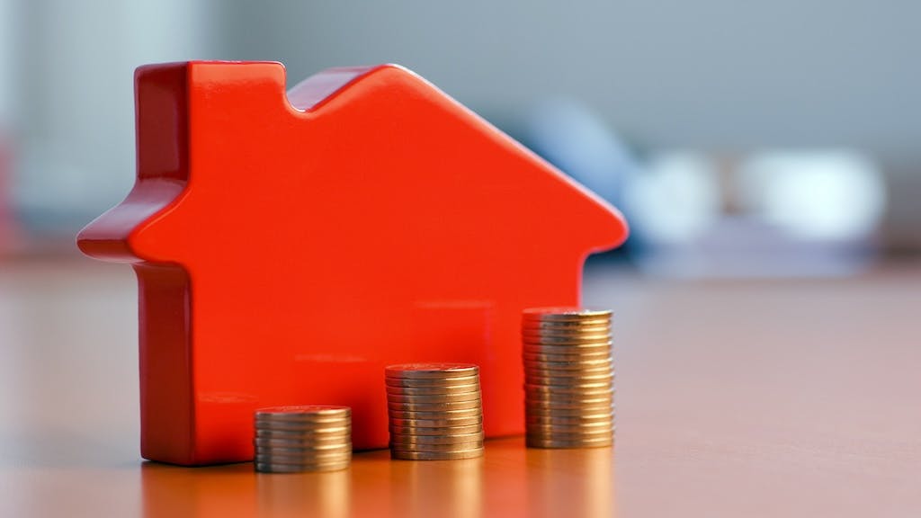 A red model home with coins stacked in ascending order