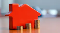 A red model home with coins stacked in ascending order