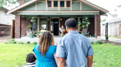 A family stands looking at their front of their home