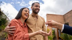 A smiling couple is handed a pair of house keys by their real estate agent A smiling couple is handed a pair of house keys by their real estate agent