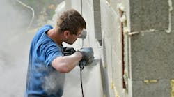 Construction worker without a face mask cuts concrete block, creating clouds of silica dust Construction worker without a face mask cuts concrete block, creating clouds of silica dust