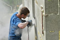 Construction worker without a face mask cuts concrete block, creating clouds of silica dust Construction worker without a face mask cuts concrete block, creating clouds of silica dust