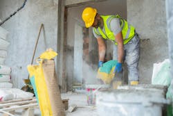 Construction worker shaking cement from bag into a bucket and creating clouds of silica dust in the process Construction worker shaking cement from bag into a bucket and creating clouds of silica dust in the process