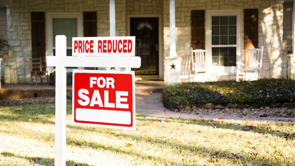 A home with a sign in the front yard that indicates that it's for sale price has been reduced