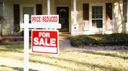 A home with a sign in the front yard that indicates that it's for sale price has been reduced