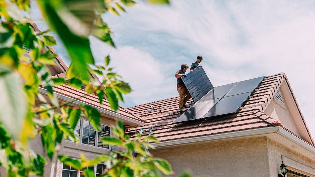 Construction workers installing solar panels on the roof of a home