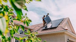 Construction workers installing solar panels on the roof of a home Construction workers installing solar panels on the roof of a home