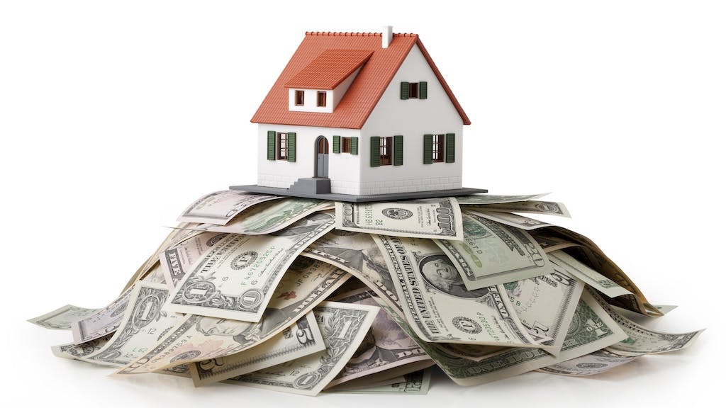 A model home sitting on a pile of money