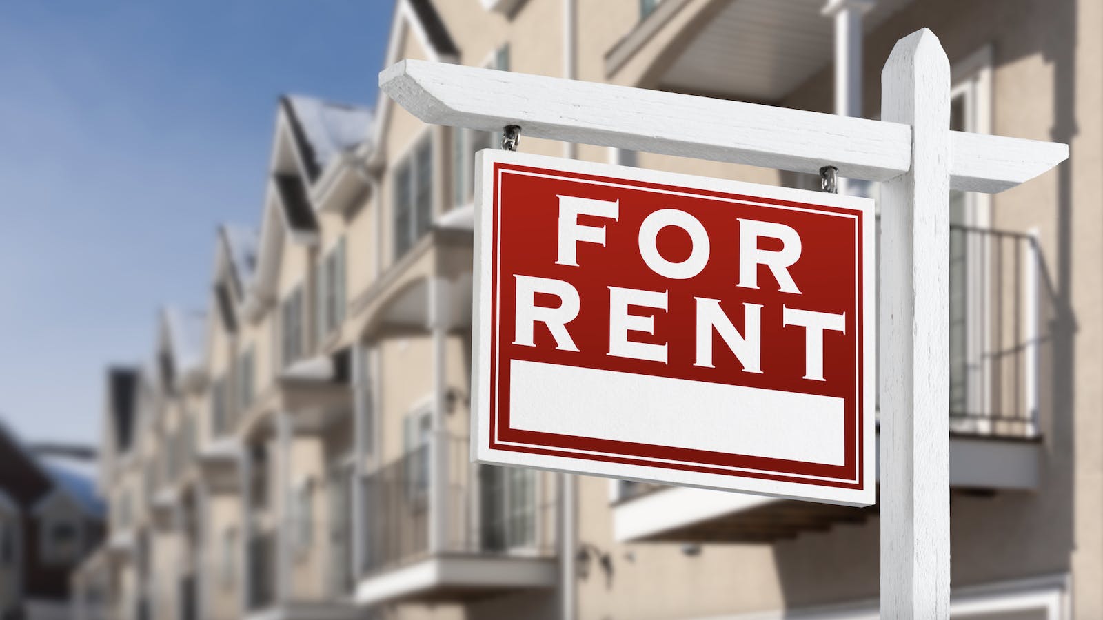 'For rent' sign in front of a row of homes for rent
