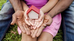 A child's and an adult's hands hold a model house with a red roof to represent fair housing opportunities A child's and an adult's hands hold a model house with a red roof to represent fair housing opportunities