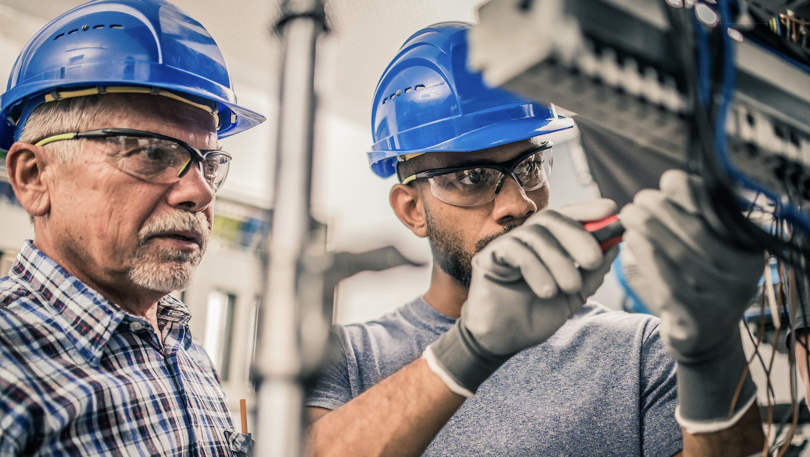 Male apprentice connects wires in a distribution board as part of his training in the skilled trades for home building.
