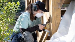 A student works with a sander at a construction site. A student works with a sander at a construction site.