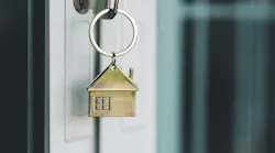 A key with a brass house keyring in the front door of a home represents pending home sales, which declined in January 2025