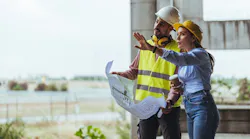 Two construction workers looking over plans at a jobsite as the construction sector sees steady job growth