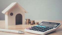 A wooden model house, calculator, pen, and stacks of coins represent the rising cost of housing, with insurance premiums making up a growing part of that cost A wooden model house, calculator, pen, and stacks of coins represent the rising cost of housing, with insurance premiums making up a growing part of that cost