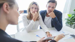 A couple looks stressed as they speak with a real estate agent about buying a home