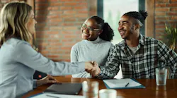 Gen-Z couple shake hands with a real estate agent as they purchase a home.