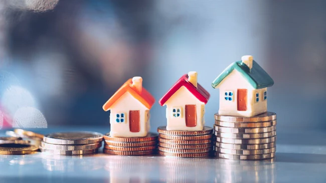 Model homes with stacks of coins underneath them indicate rising housing costs and limited housing affordability.