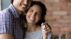 Hispanic couple smiling and holding up keys to a new home as the Hispanic homeownership rate hits a record high.