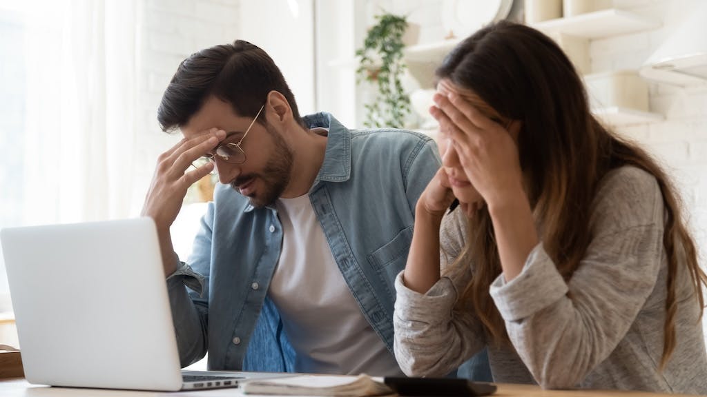 A couple looks stressed as they look over their finances and realize homeownership isn't possible.