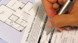A person filling out a mortgage application as the rate of mortgage applications declines.