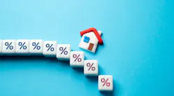 A model home sits above cubes with percentage symbols on them, indicating a change in mortgage rates