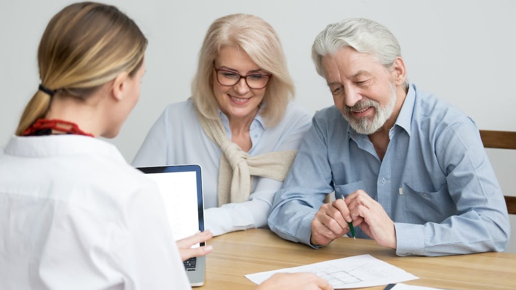 A Baby Boomer couple discussing purchasing a home with a real estate agent.