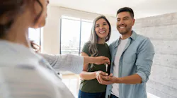 A sales associate makes a home sale and hands the new homeowners their keys.