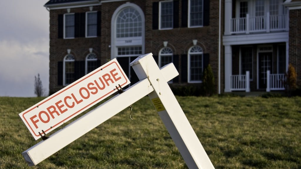 A suburban home with a foreclosure sign in the front yard
