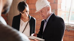 Home builder wearing a hard hat speaks with clients on the jobsite. Home builder wearing a hard hat speaks with clients on the jobsite.