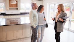 A real estate agent shows prospective homebuyers around a home A real estate agent shows prospective homebuyers around a home