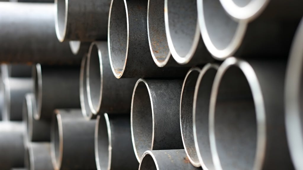 Closeup of stacked metal pipe as construction costs rise.