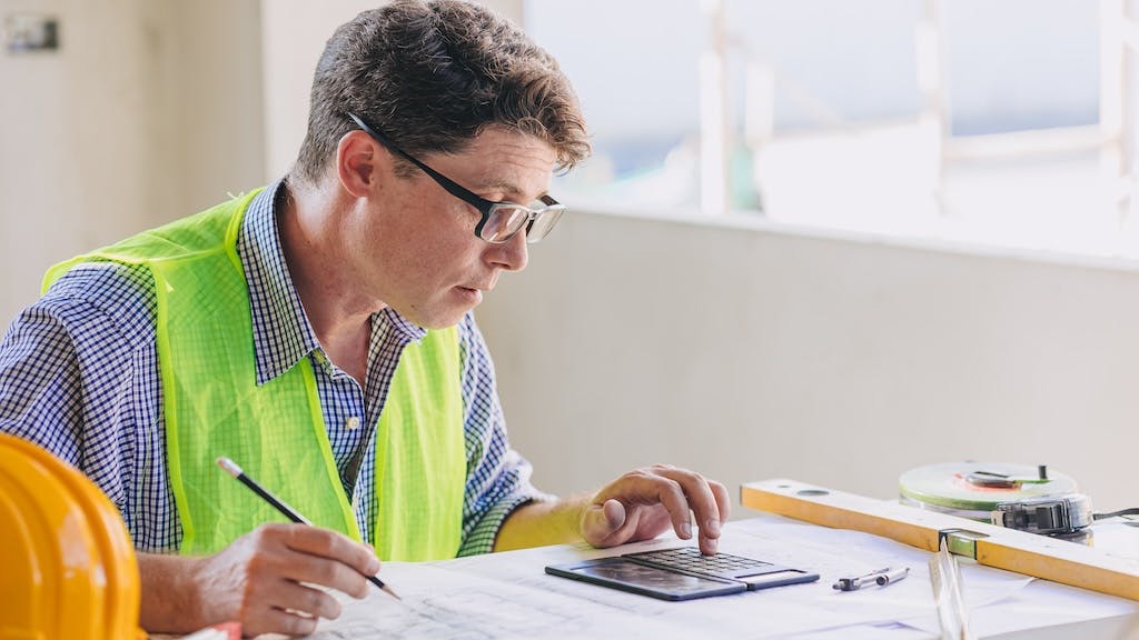 A builder calculating costs for rental construction.