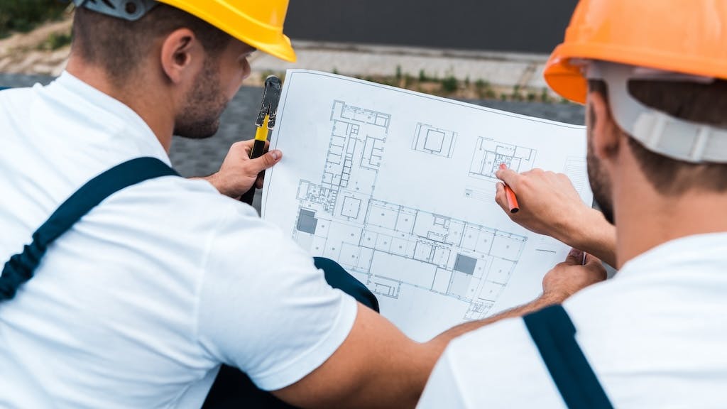 Home builders working together to figure out a home's floor plan so it is less expensive to build.