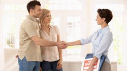 A real estate agent shaking hands with a couple after a recent home sale. A real estate agent shaking hands with a couple after a recent home sale.
