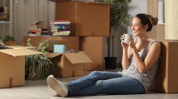 Gen-Z woman sitting on the floor surrounded by moving boxes