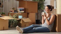 Gen-Z woman sitting on the floor surrounded by moving boxes Gen-Z woman sitting on the floor surrounded by moving boxes