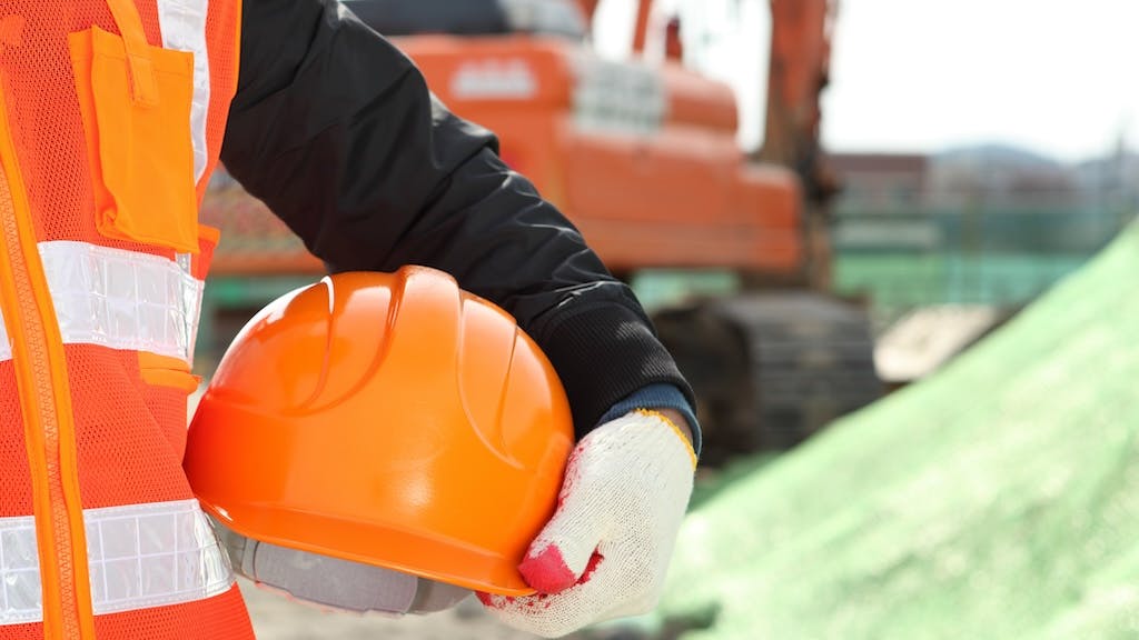 Closeup of hard hat being held by construction worker as part of on-site safety measures.