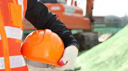Closeup of hard hat being held by construction worker as part of on-site safety measures.