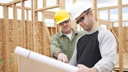 Two home builders discuss plans at the site of a new home Two home builders discuss plans at the site of a new home