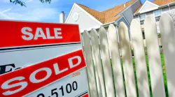 A home with a white picket fence has a 'sold' sign in the front yard