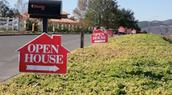 Open house signs along a street point toward homes for sale as existing-home sales decrease.