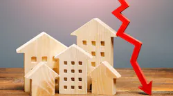 An arrow descending next to several wooden model homes indicates falling home prices