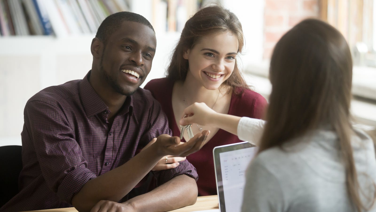 A young couple takes the keys from a real estate agent for their new home