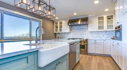 A modern white kitchen with large window letting in natural light