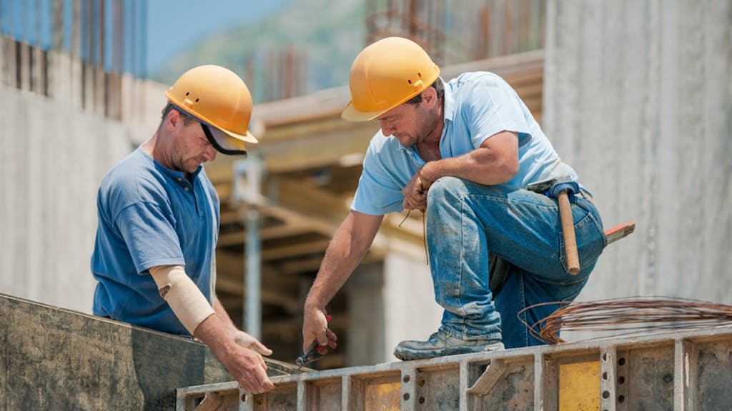 Two high-earning construction workers collaborate at a jobsite