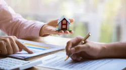 A homebuyer signs papers with a real estate agent